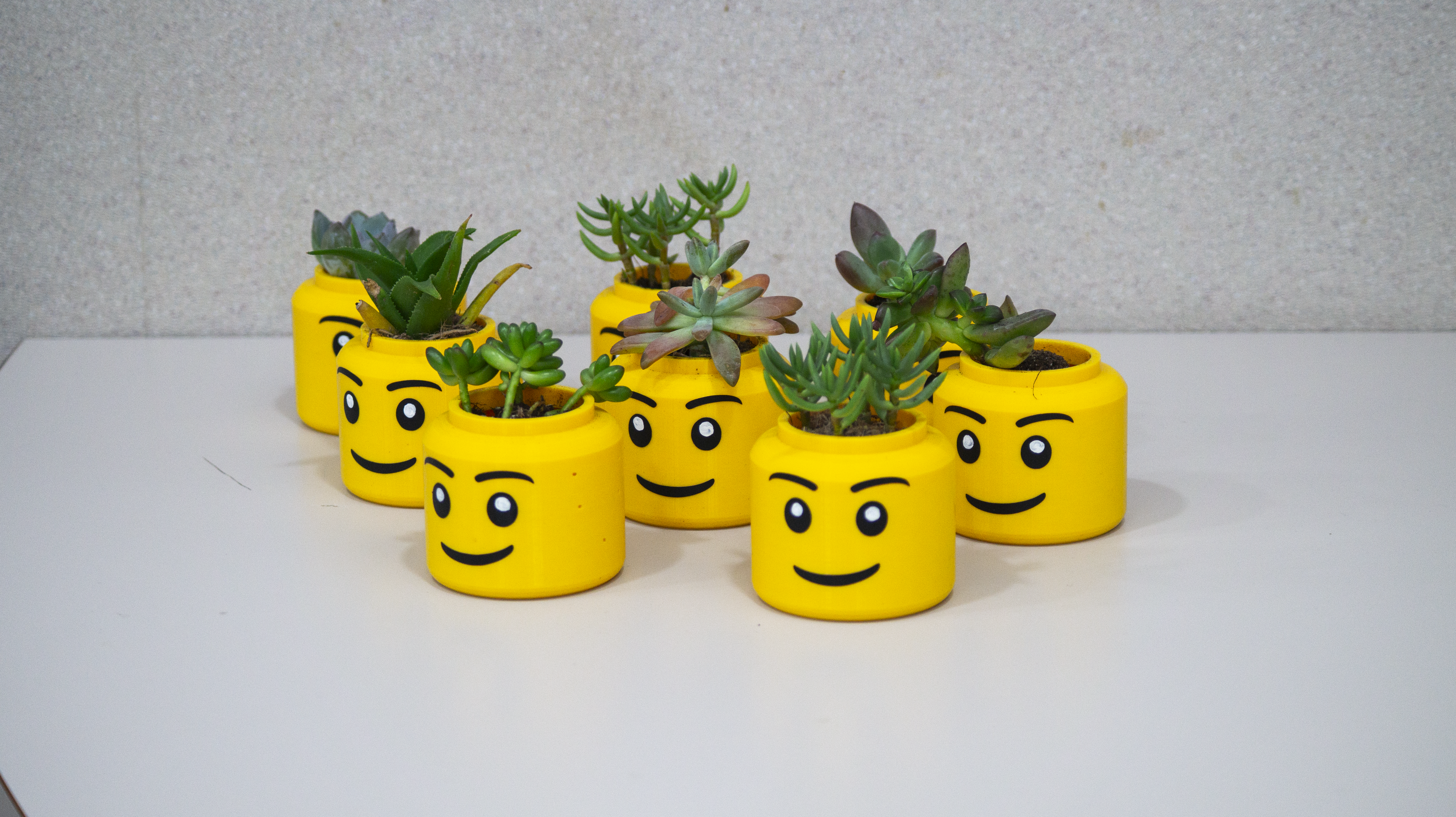 Yellow Lego head planters with succulents in them