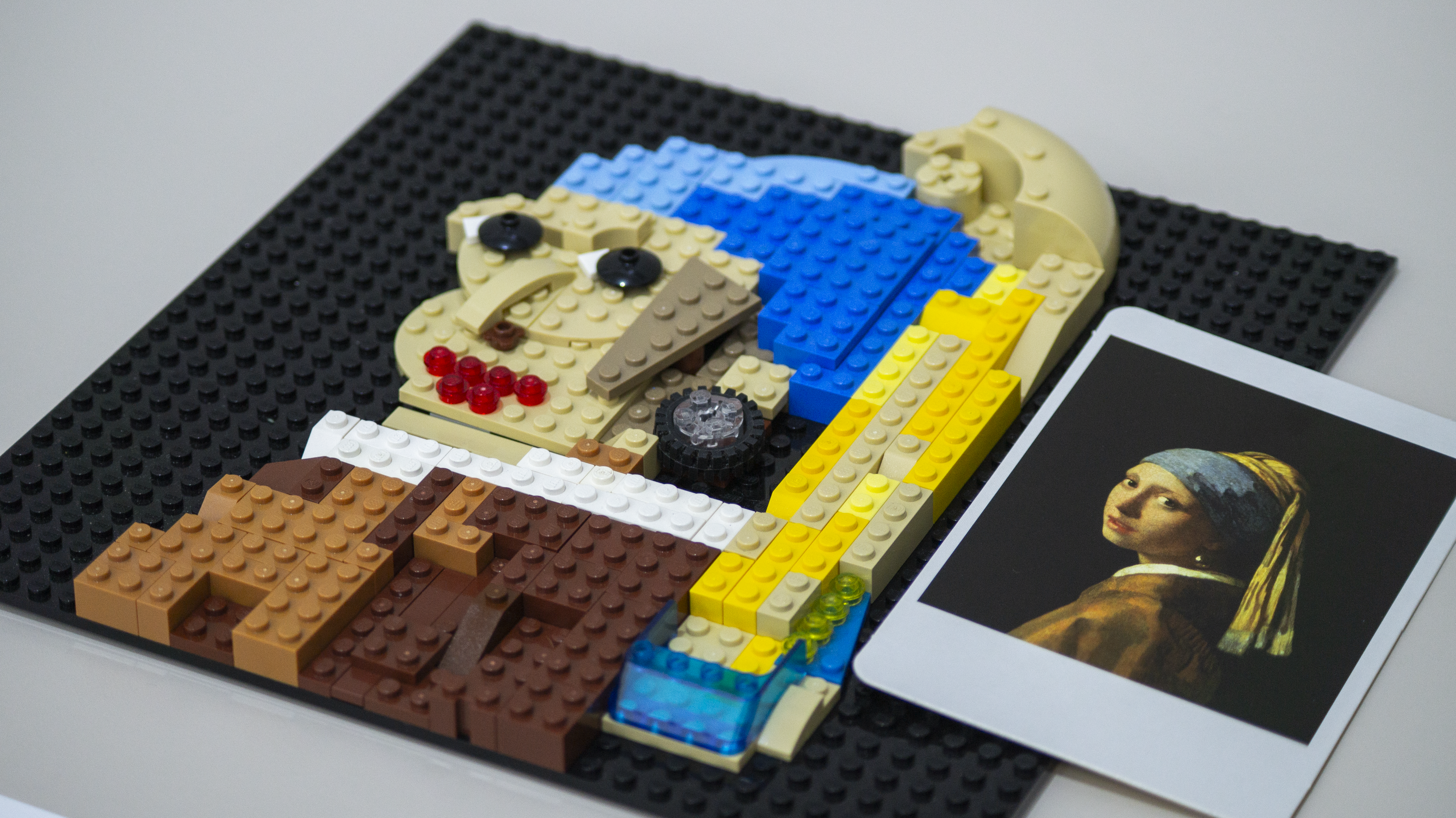 A Lego creation of the famous painting "Girl with a Pearl Earring" but with a wheel for the earring