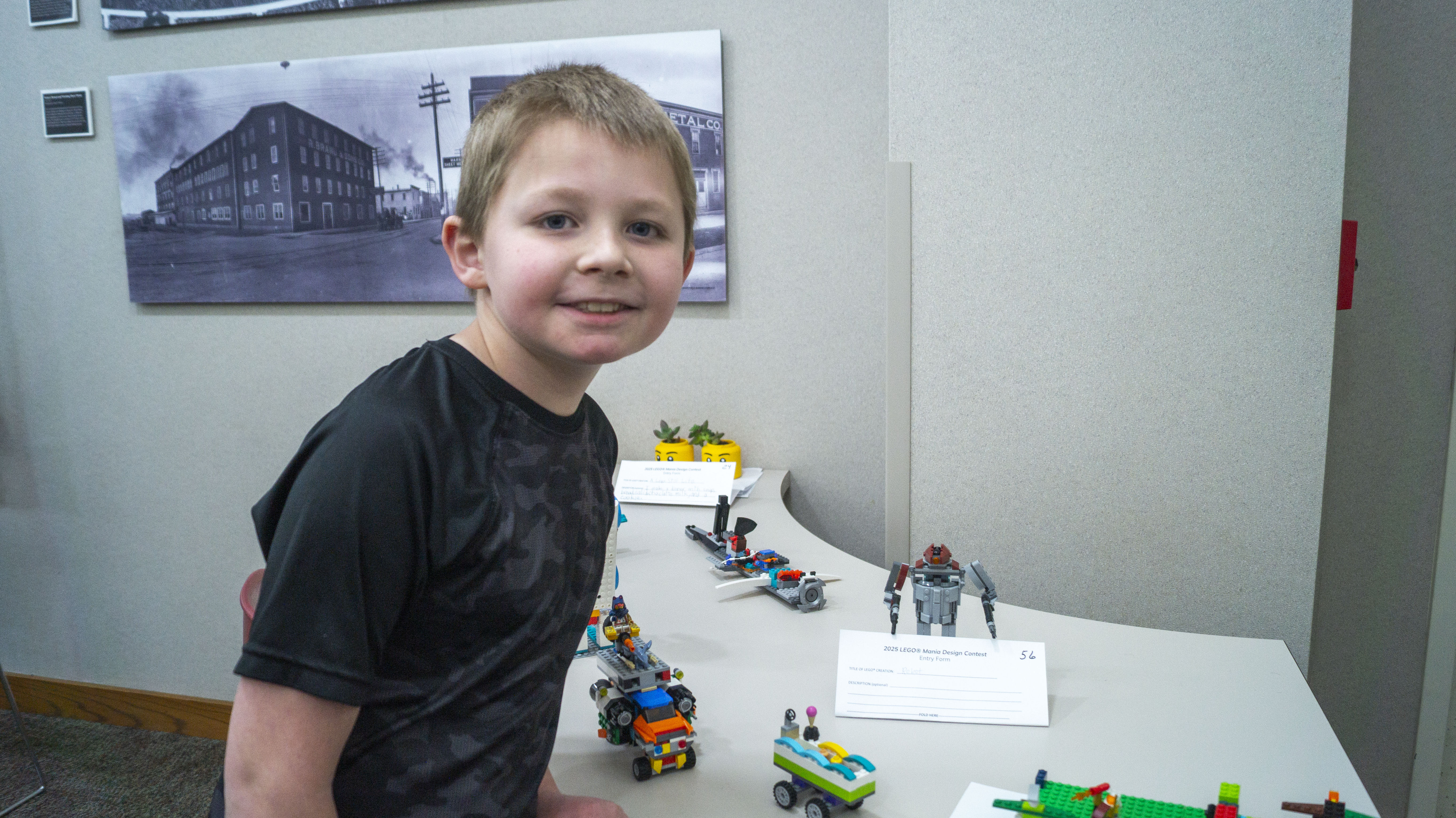 A boy standing next to his Robot Lego creation