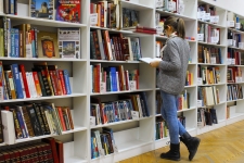 Explora for Everyone resource image showing a woman standing by a book shelf with a book in her hands in what looks to be a library
