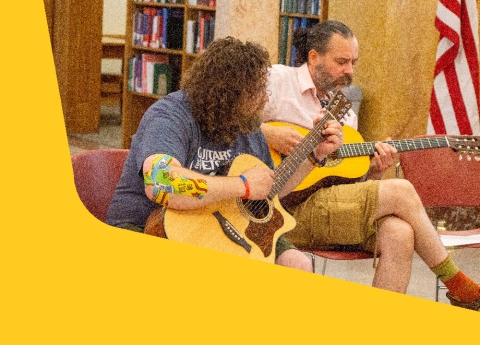 Two adults playing guitar under the dome